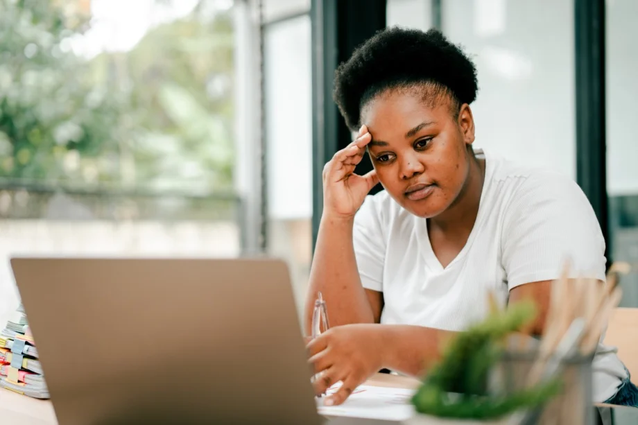 A frustrated nonprofit worker stares at her laptop while working in a coffee shop.