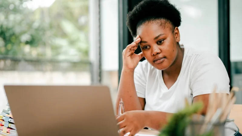 A frustrated nonprofit worker stares at her laptop while working in a coffee shop.